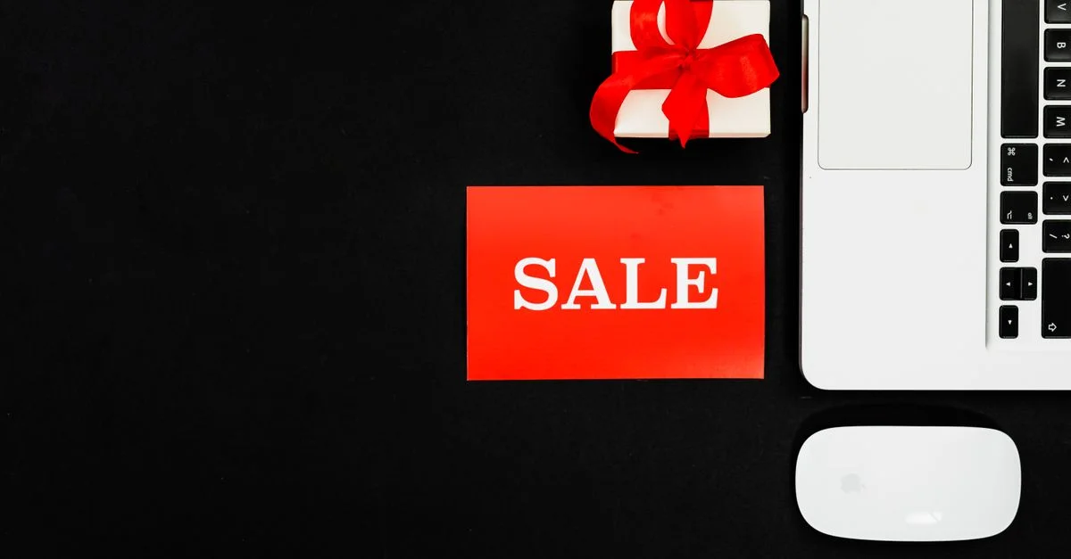 Vue de dessus d'un ordinateur portable, d'une boîte cadeau et d'un panneau de soldes pour promotion en ligne.