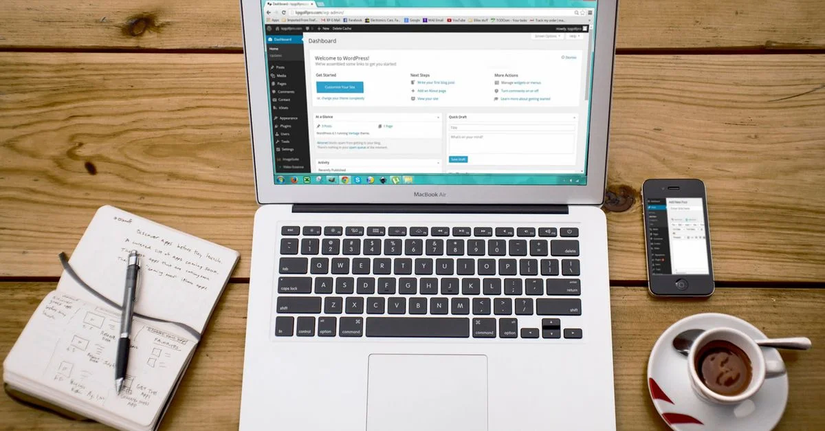 Une scène de bureau à domicile confortable avec un ordinateur portable, un carnet, un smartphone et un café, parfaite pour la productivité.
