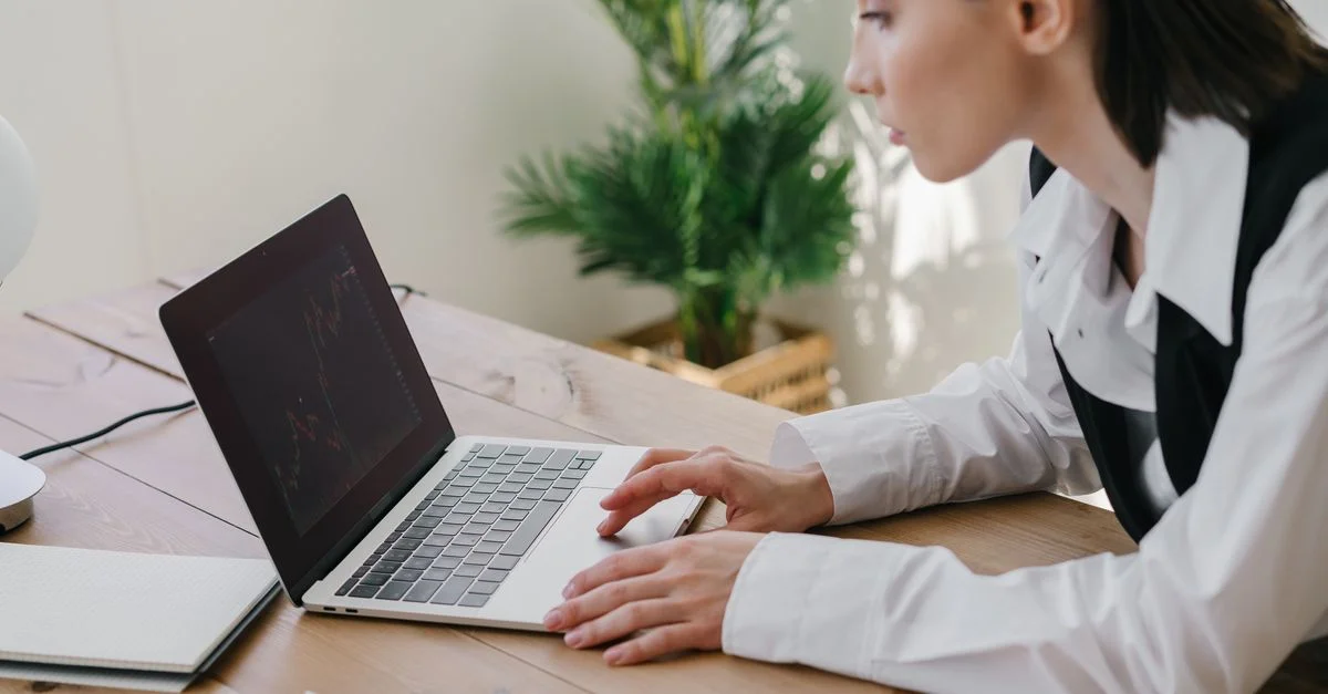 Femme d'affaires travaillant sur des graphiques du marché boursier dans un bureau moderne avec un portable et des graphiques.
