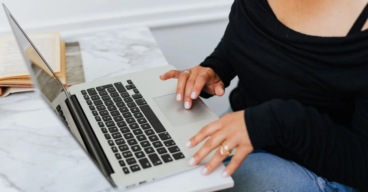 Une personne utilisant un ordinateur portable sur un bureau en marbre, tapant et se concentrant sur son travail à l'intérieur.